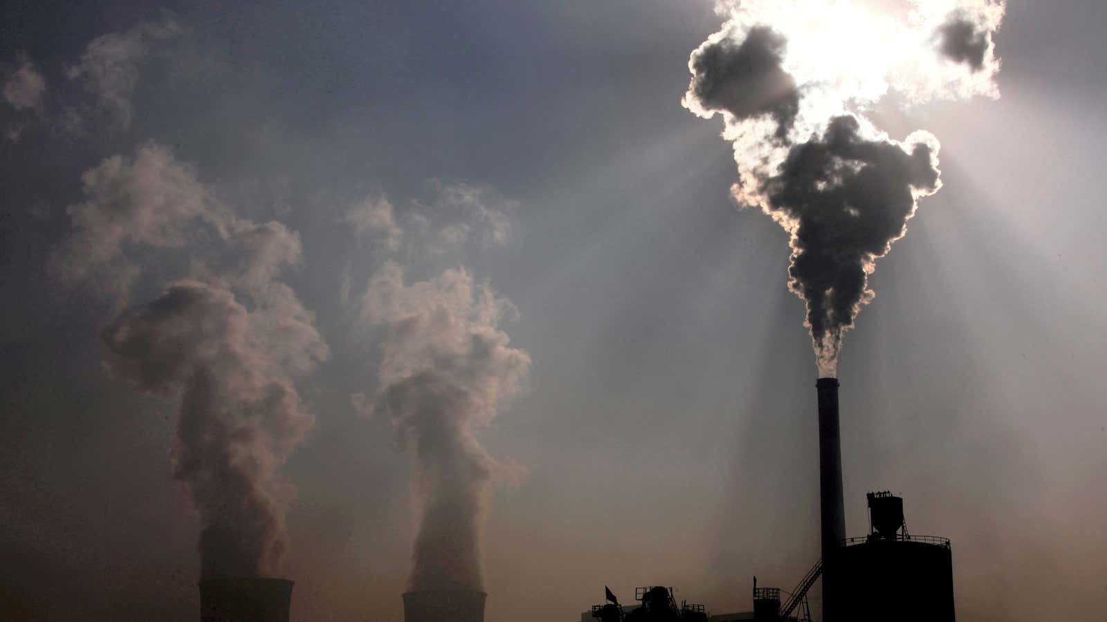FILE PHOTO: A coal-burning power plant can be seen behind a factory in China’s Inner Mongolia Autonomous Region, October 31, 2010. REUTERS/David Gray/File Photo
