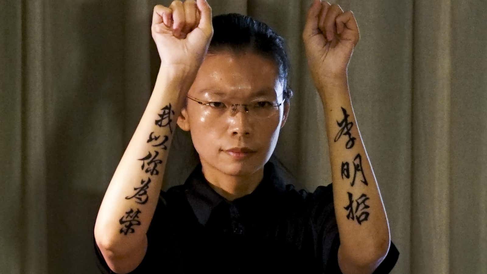 Lee Ming-che’s wife with tattoos on her arms that say: “Lee Ming-Che, I’m proud of you.”