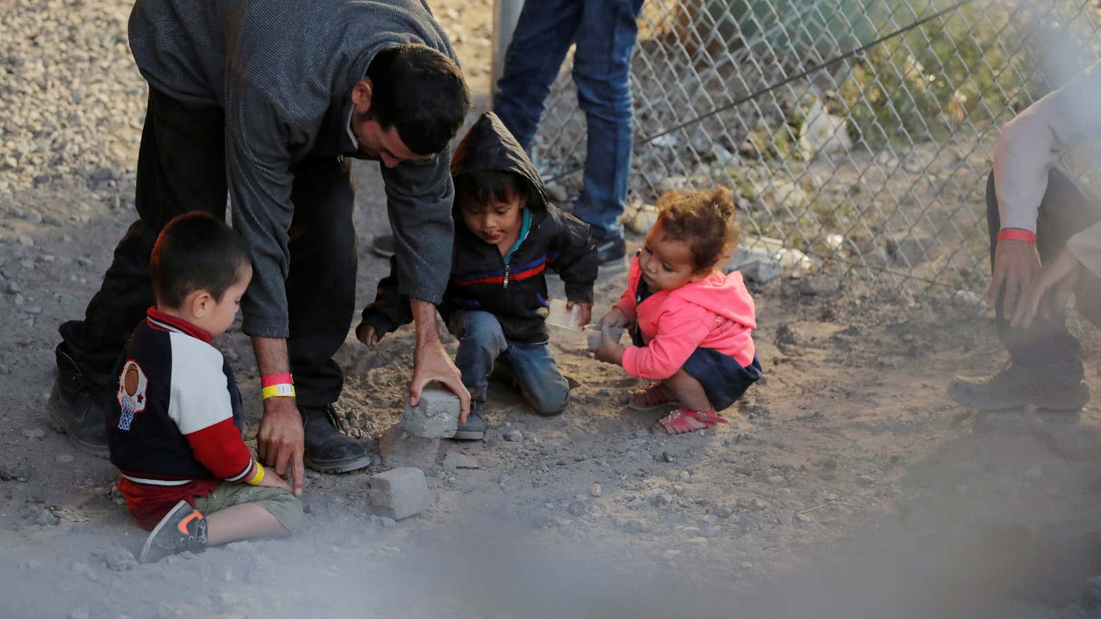 A man gives children rocks to play with inside an enclosure, where they were being held by U.S. Customs and Border Protection in El Paso, Texas.