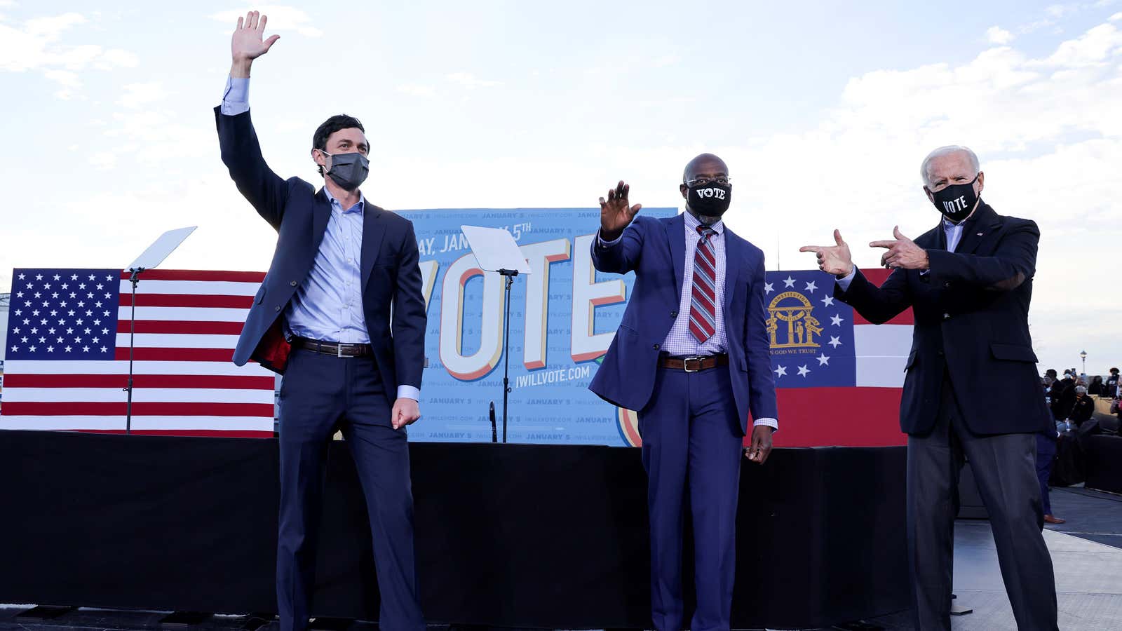 U.S. President-elect Joe Biden points to Democratic U.S. Senate candidates from Georgia Jon Ossoff and Raphael Warnock onstage in front of a banner that says…