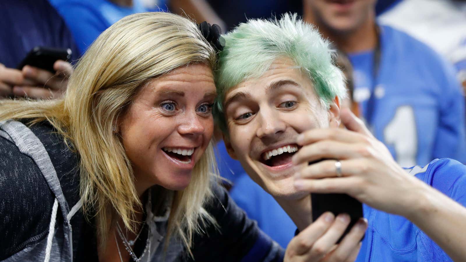 Tyler “Ninja” Blevins takes photographs with fans before an NFL football game.