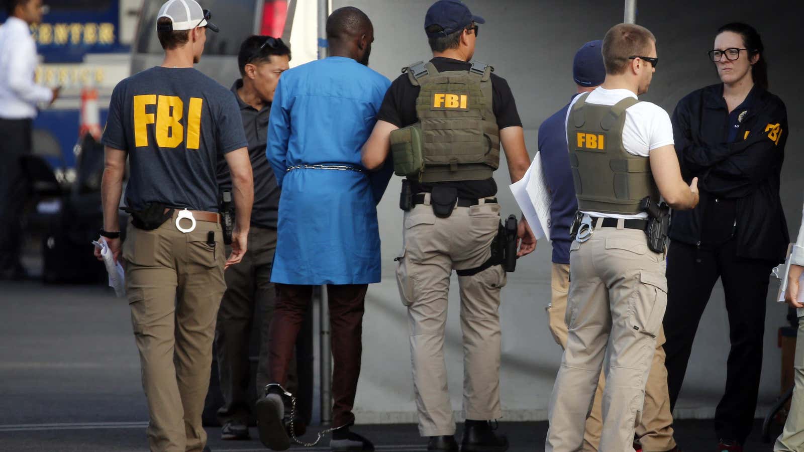 Federal agents hold a detainee, second from left, at a downtown Los Angeles parking lot after predawn raids Aug. 22, 2019