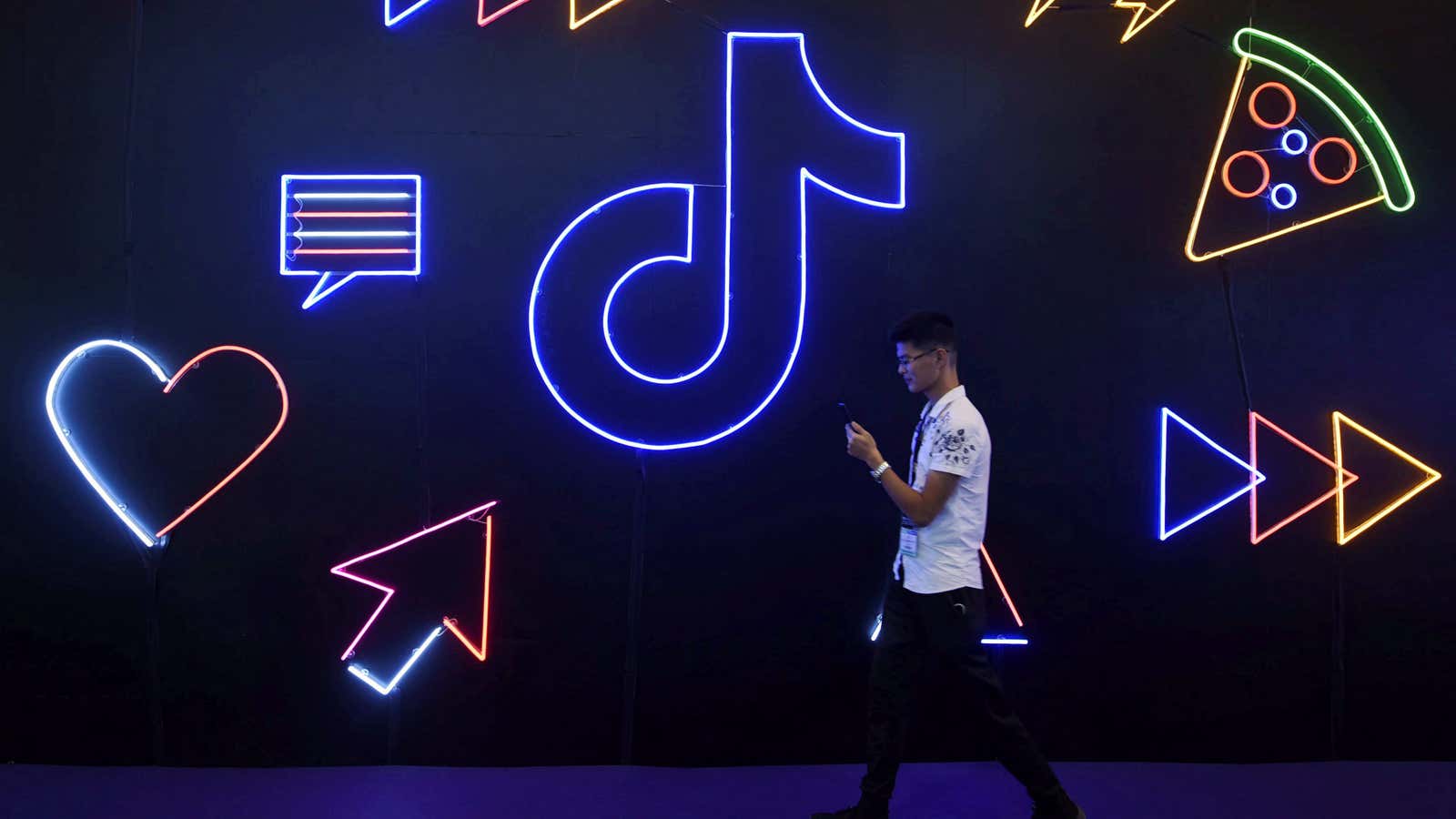A man holding a phone walks past a sign of Chinese company ByteDance’s app TikTok, known locally as Douyin, at the International Artificial Products Expo…
