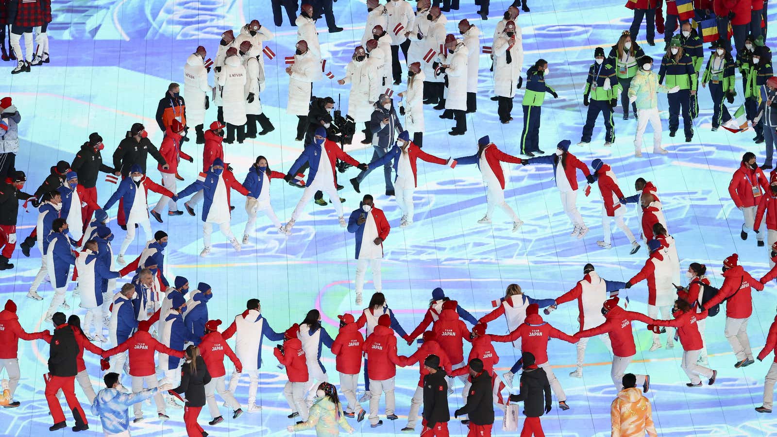 People walk around in a circles holding hands at the closing ceremony in Beijing.