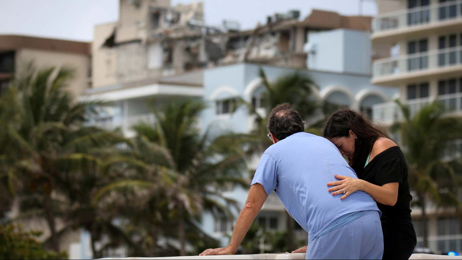 A couple react near the partially collapsed residential building in Surfside, Florida.