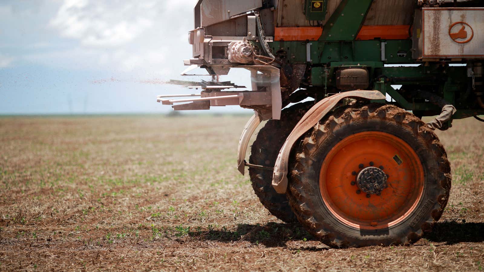 A tractor spreading fertilizer on a soybean field in Brazil.