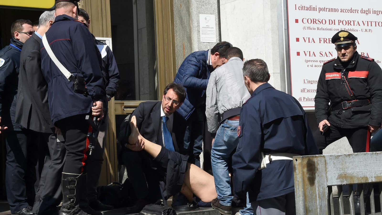 Rescuers and police help an injured person outside the tribunal building in Milan.