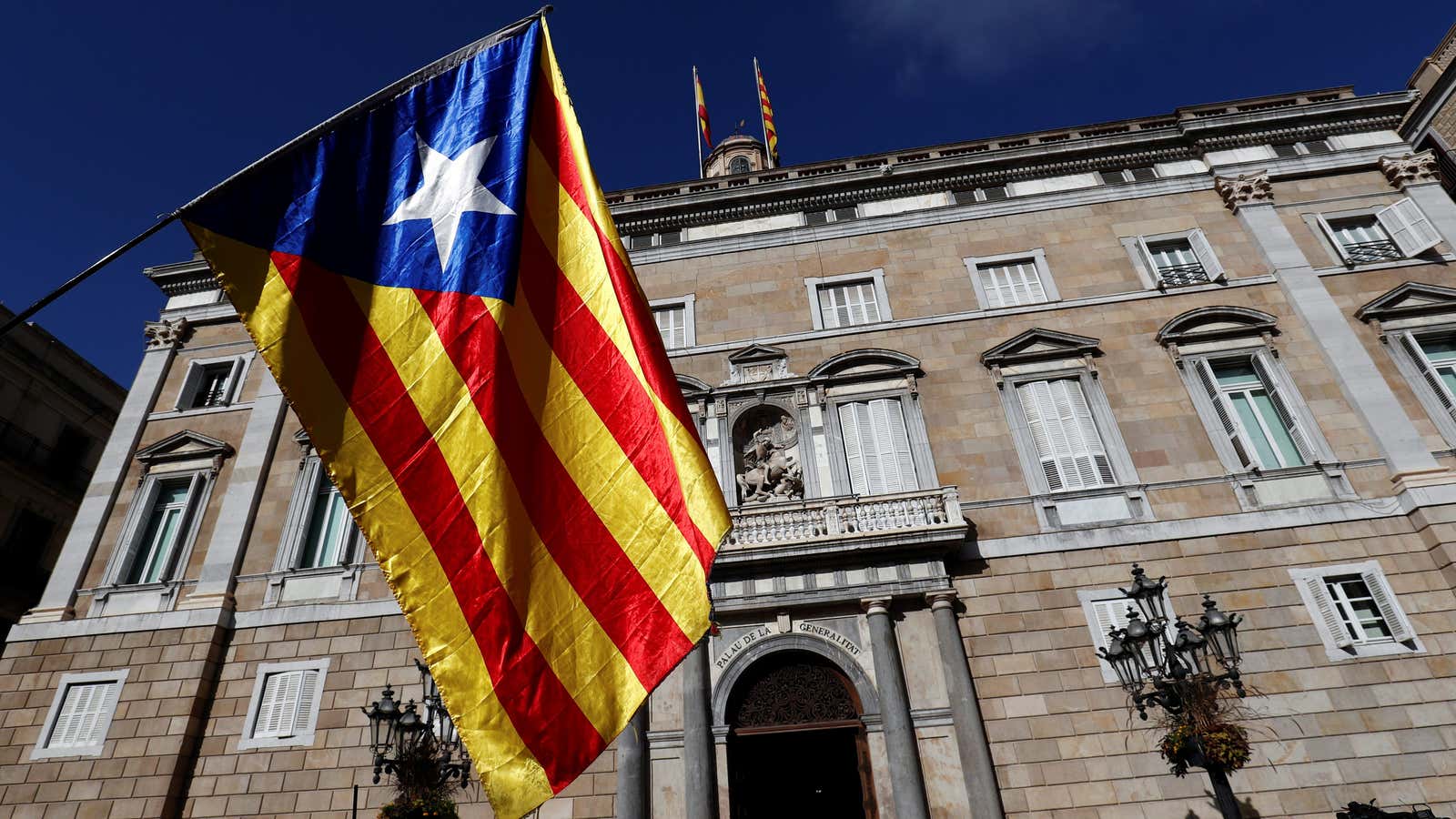 A Catalan separatist flag is waved in front of the Generalitat Palace, the Catalan regional government headquarters in Barcelona.