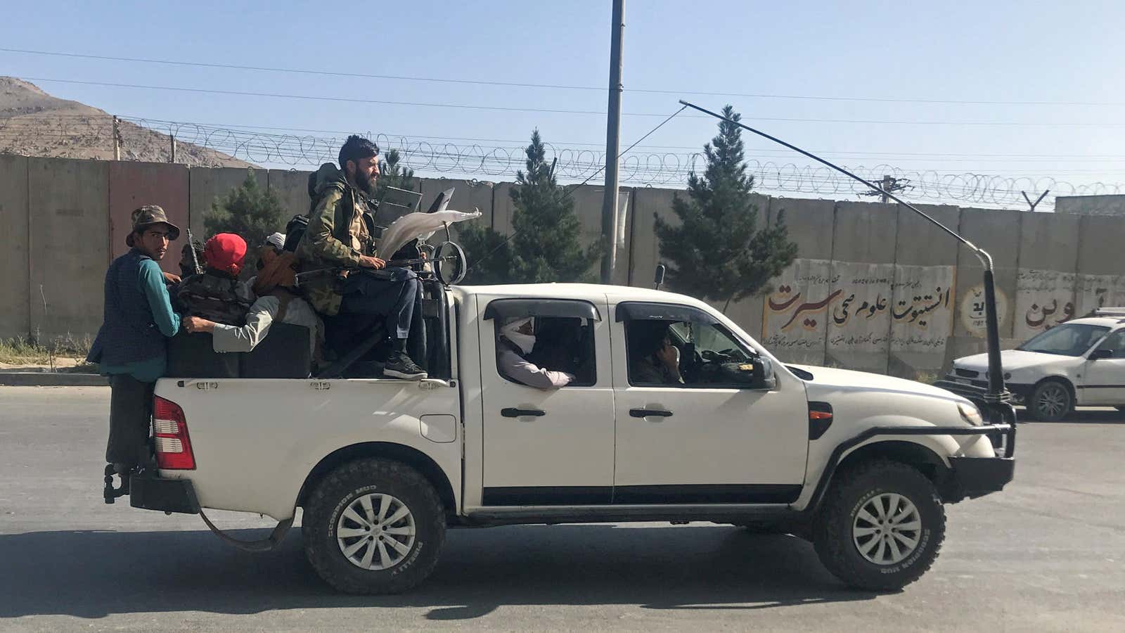 Taliban fighters ride a pick-up truck into Kabul