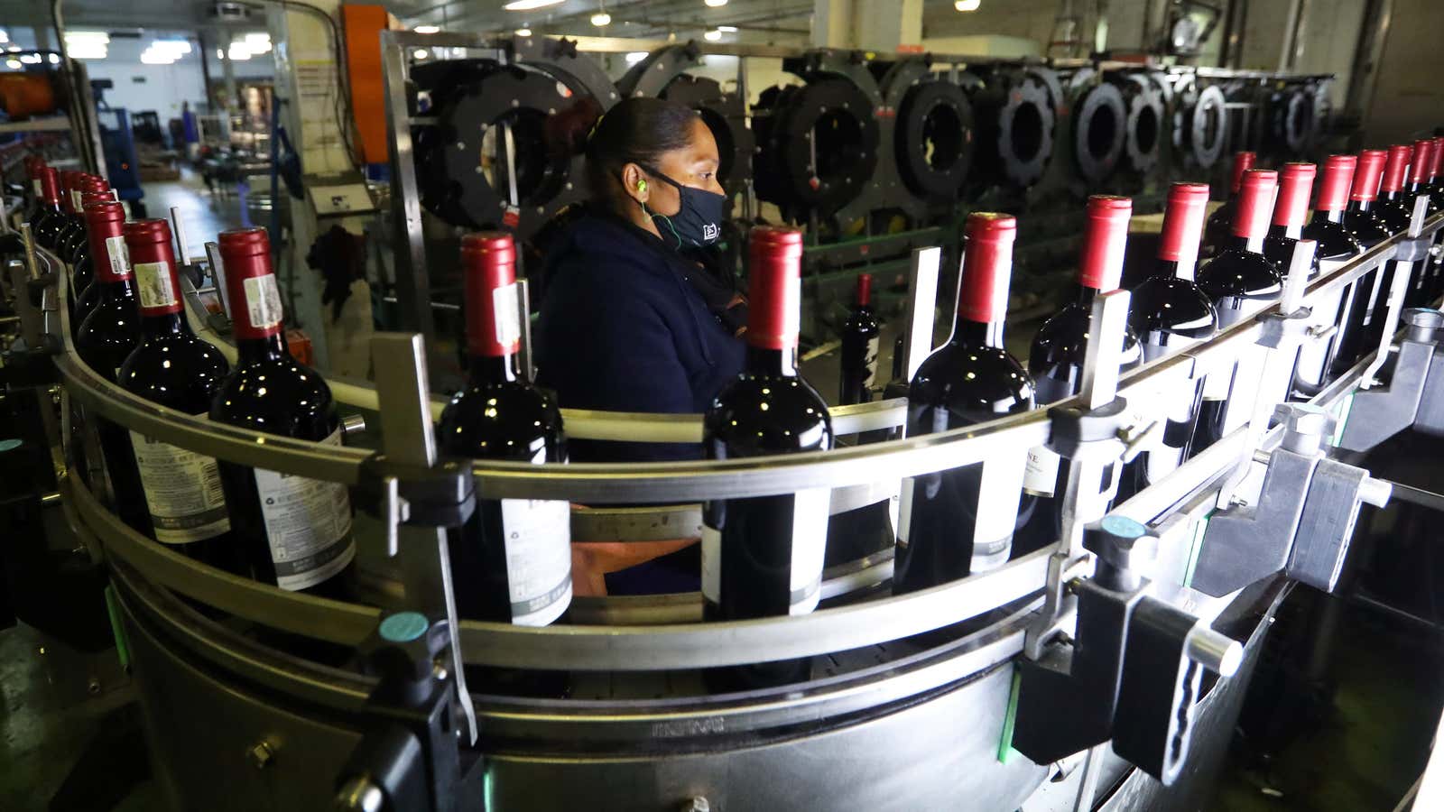 A worker checks bottles of wine coming out of a production line at Nederburg Wine Estate in Paarl, South Africa, July 8, 2020.