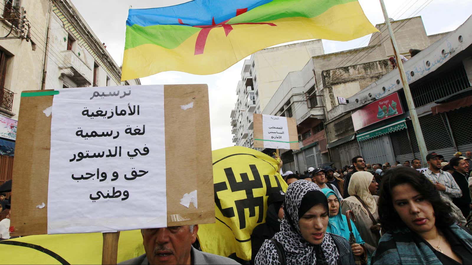 People from Amazigh, north of Morocco, hold a Amazigh flag and a banner, that reads, “the Amazigh language is a statutory right and acquired.”