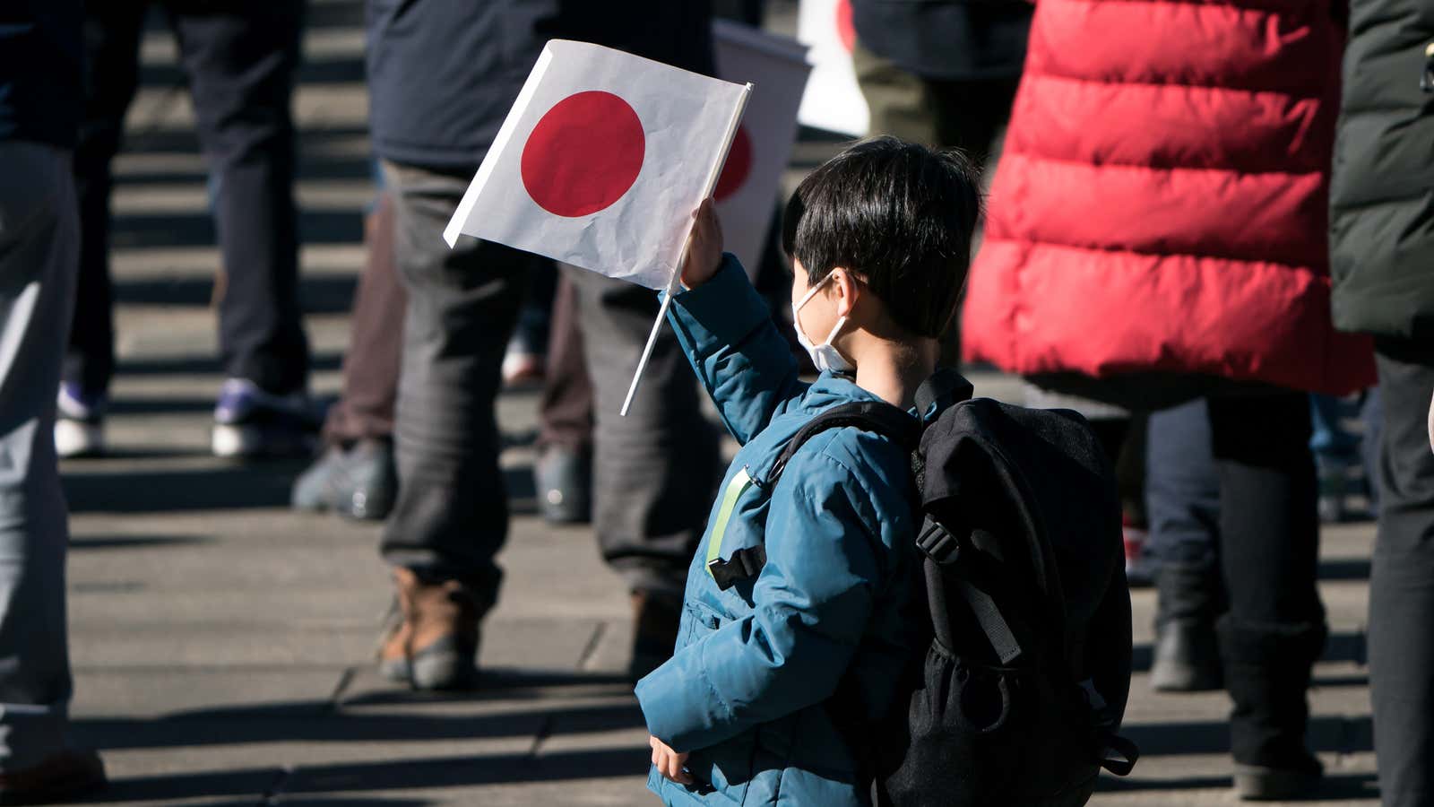 A boy holds a Japanese national flag during the New Year&#39;s appearance by the Japanese royal family at the Imperial Palace on January 2, 2023.
