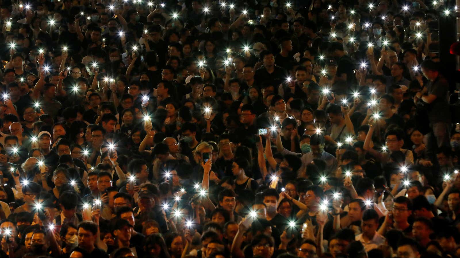 Hong Kong protestors hold up their cellphones at a rally.
