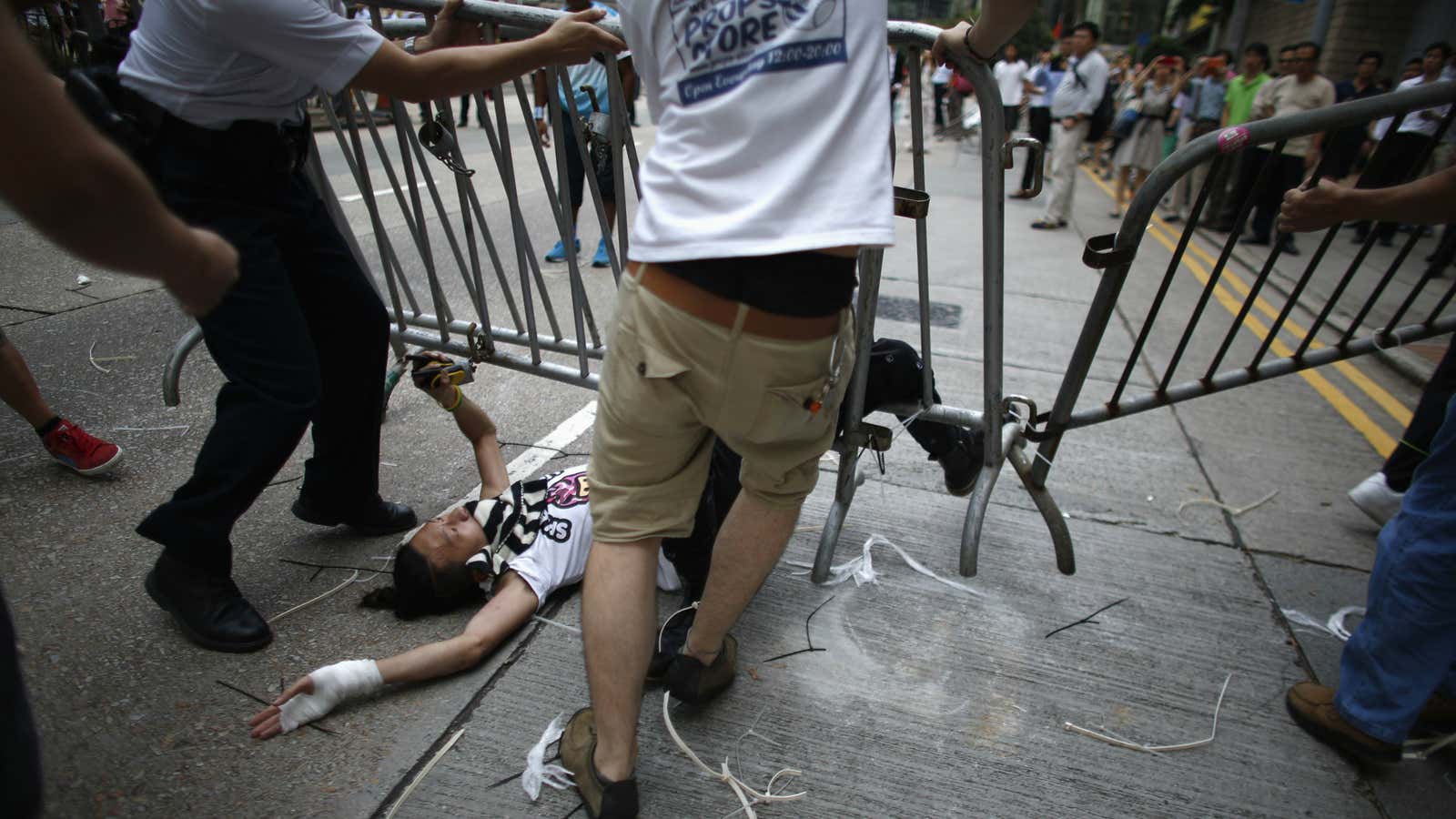 Anti-Occupy protesters drag a metal fence over a pro-democracy protester in central Hong Kong on Monday.