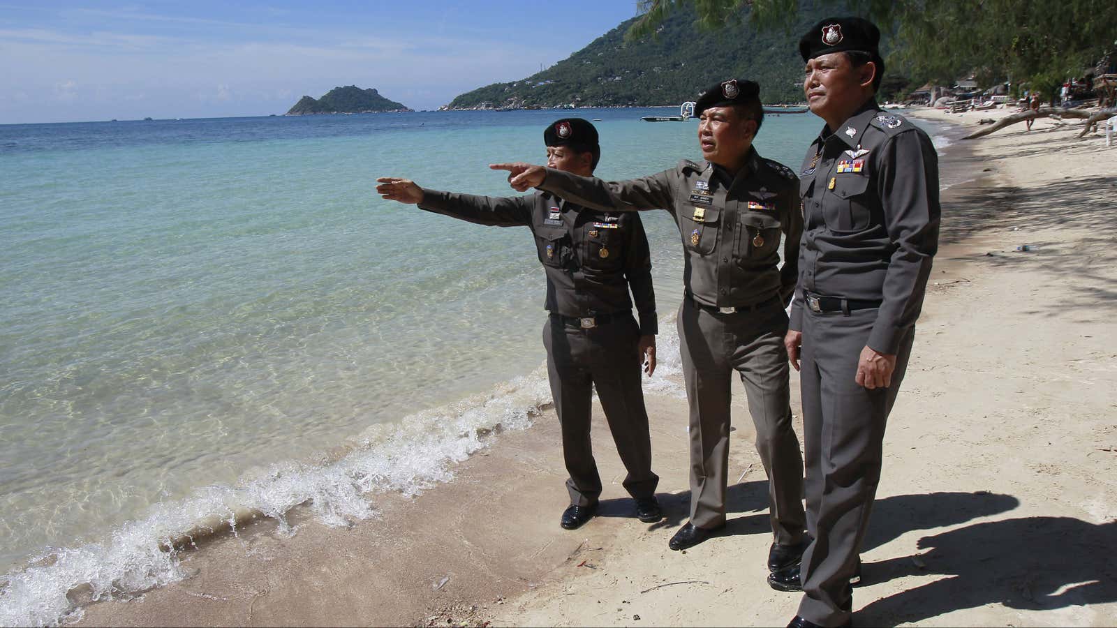 Chief of Royal Thai Police Somyot Pumphanmuang (C) and Royal Thai Police advisor Jarumporn Suramanee (L) look at a beach near the spot where bodies of two killed British tourists were found.