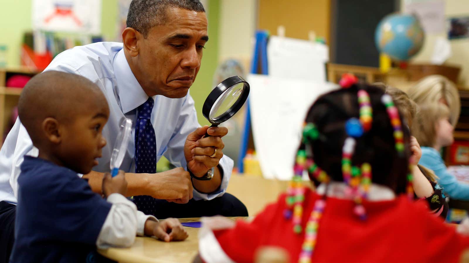 U.S. President Barack Obama uses a magnifying glass to play a game with children in a pre-kindergarten classroom at College Heights early childhood learning center…