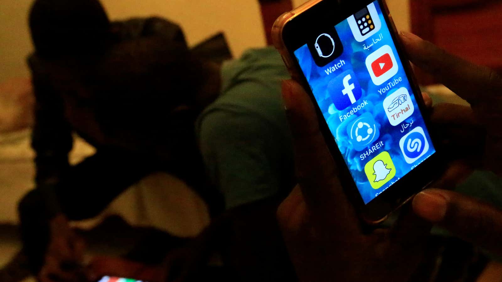 A Sudanese man holds his phone with restricted internet access social media platforms, in Khartoum, Sudan