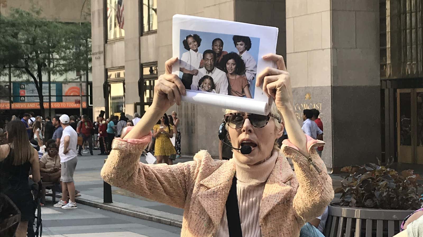 E. Jean Carroll holds a photo of Bill Cosby on her “hideous men” tour