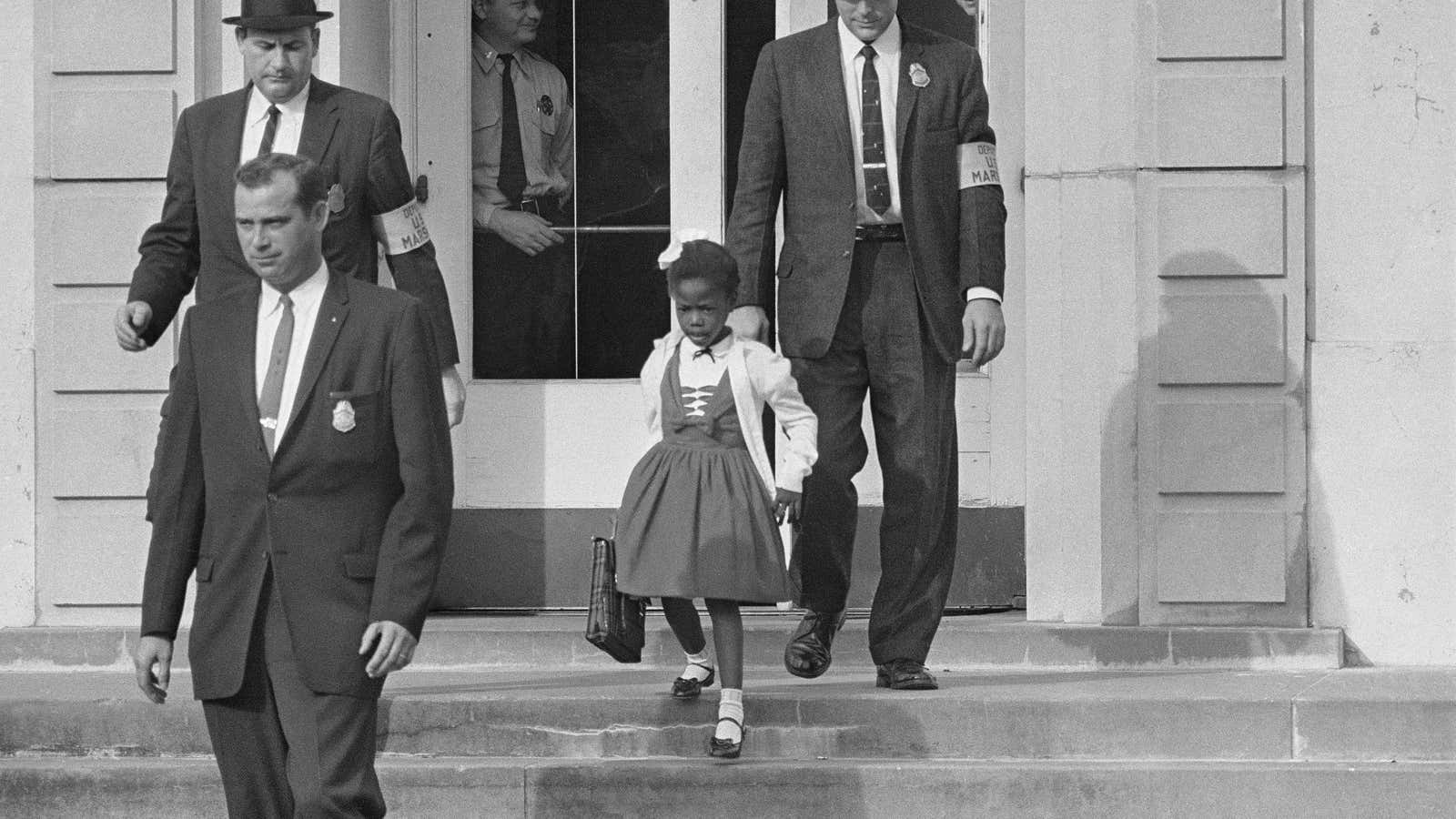 US deputy marshals escort 6-year-old Ruby Bridges from William Frantz Elementary School in New Orleans, La.  The first grader was the only black child enrolled in the schol