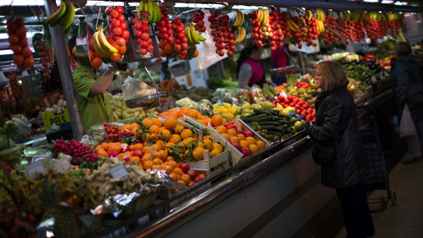 In this Thursday Jan. 17, 2013 file photo, a woman buys fruit at a market in Barcelona, Spain.