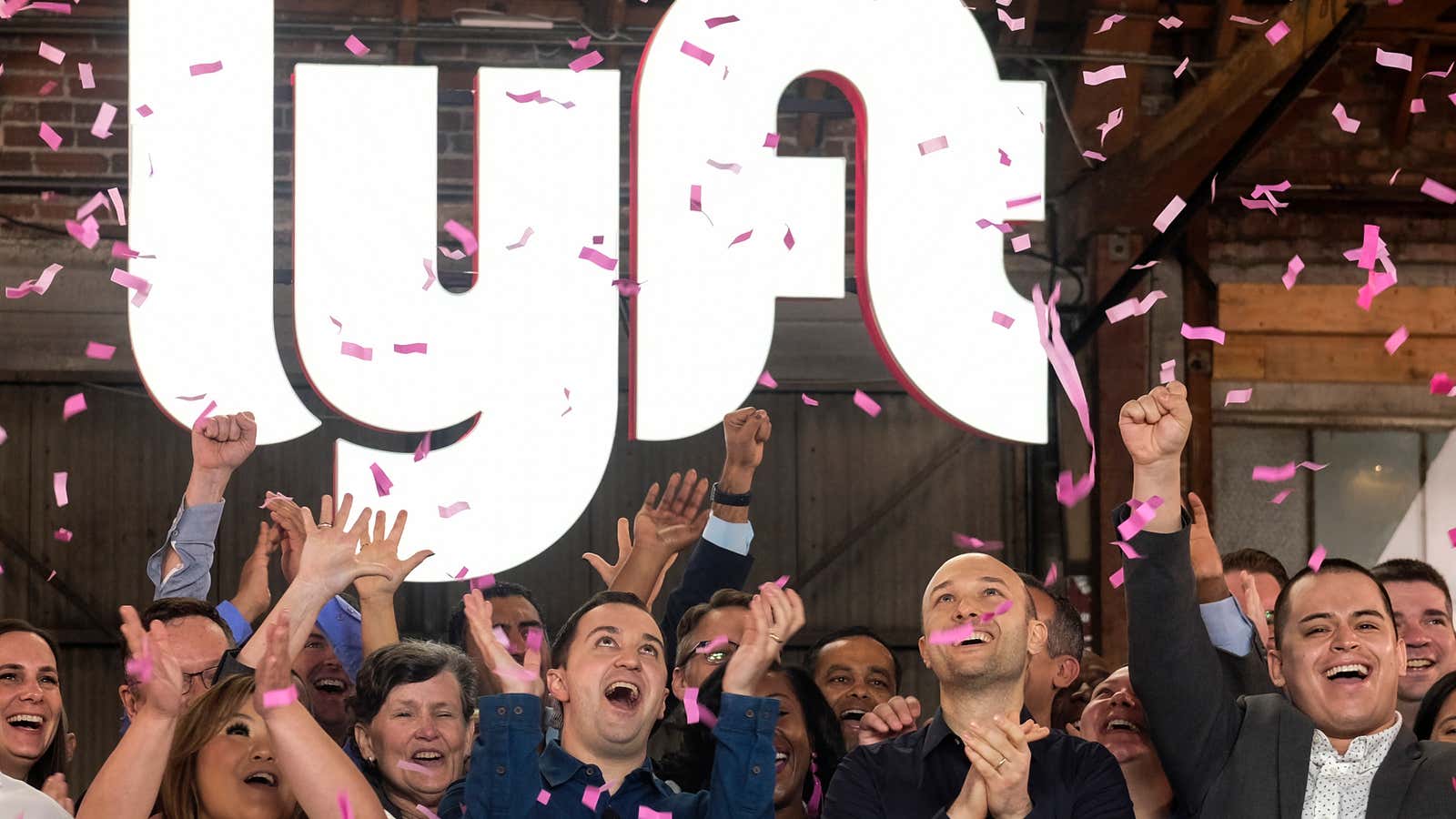 Lyft co-founders John Zimmer, front second from left, and Logan Green, front second from right, cheer as they as they ring a ceremonial opening bell…