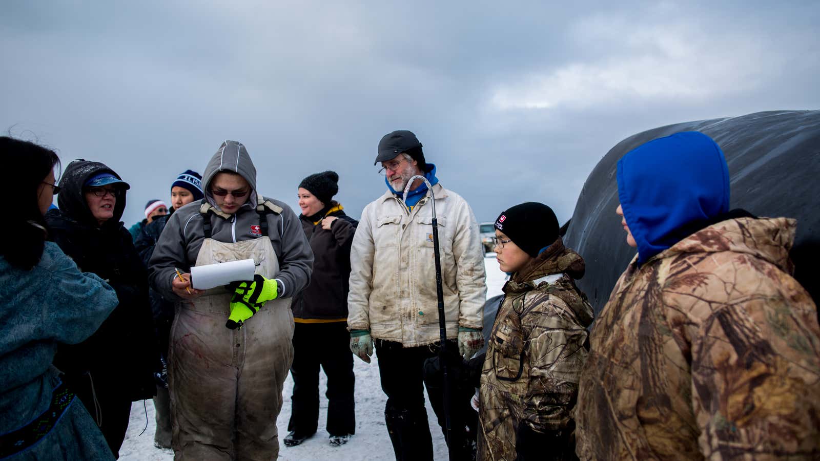 UTQIAGVIK, ALASKA - October 6, 2017:  Josiah Patkotak fills out a report for the wildlife department after successfully striking a whale with his family&#39;s crew, Patkotak Crew, while Senior Wildlife Biologist, Robert Suydam, looks on. Photo Courtesy Ash Adams.