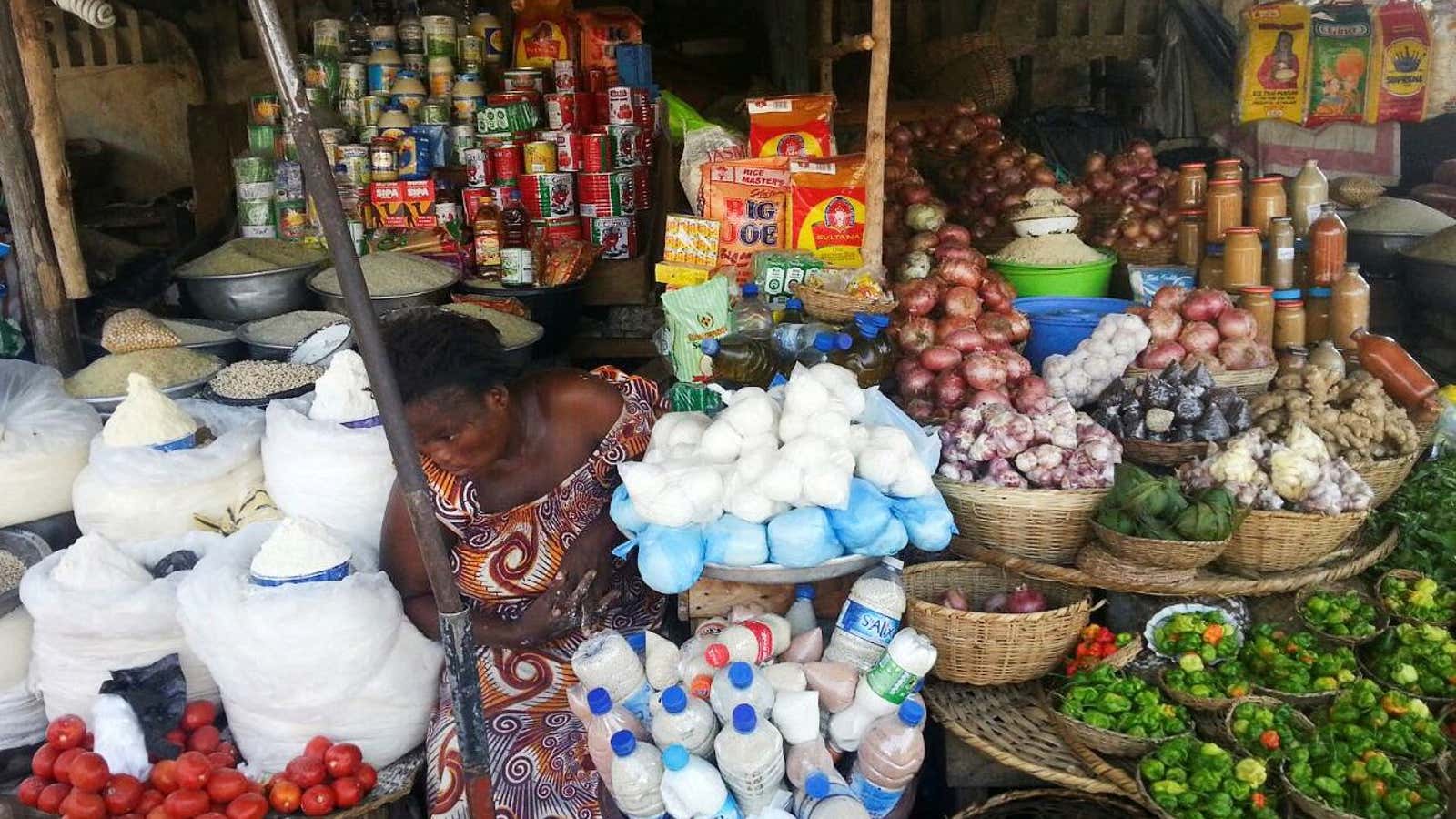 A woman sits in her market stall in Cotonou, Benin amid piles of merchandise
