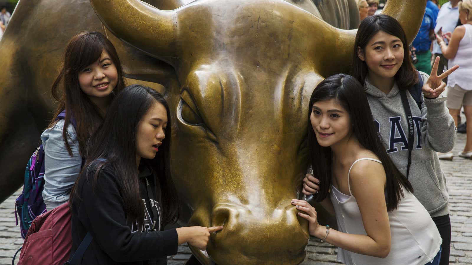 OTHER PIC OF THESE GIRLS SAYS THEY’RE CHINESE: RTX1PI34 Tourists pose for photographs with a landmark statue of a bull in New York August 24,…