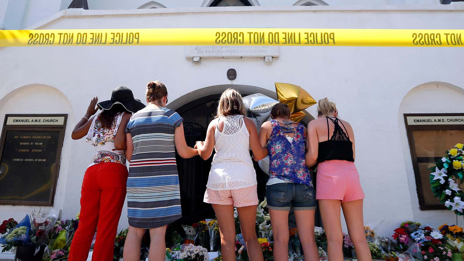 A group of women pray together in front of the Emanuel AME Church.