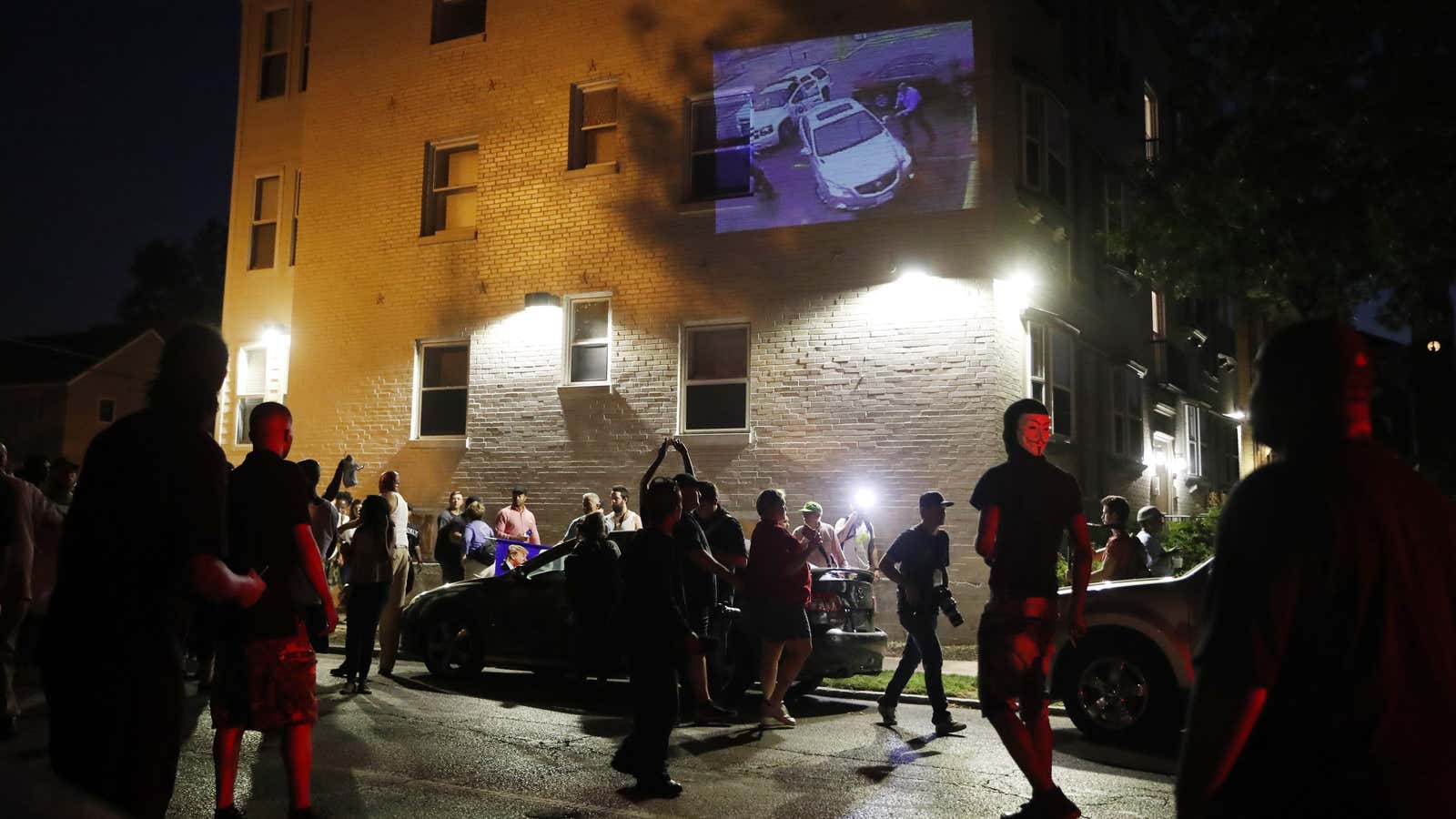 A group of protesters watch projected images on a house while marching on Sept. 16.