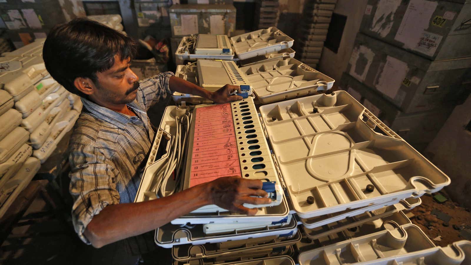 A member of election duty staff arranges an electronic voting machine (EVM) inside a strong room ahead of the 2014 general elections in the western…