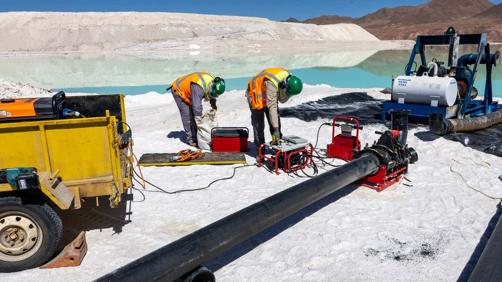 Lithium mine workers inspect machinery at an evaporation pond in the Atacama Desert, Chile.