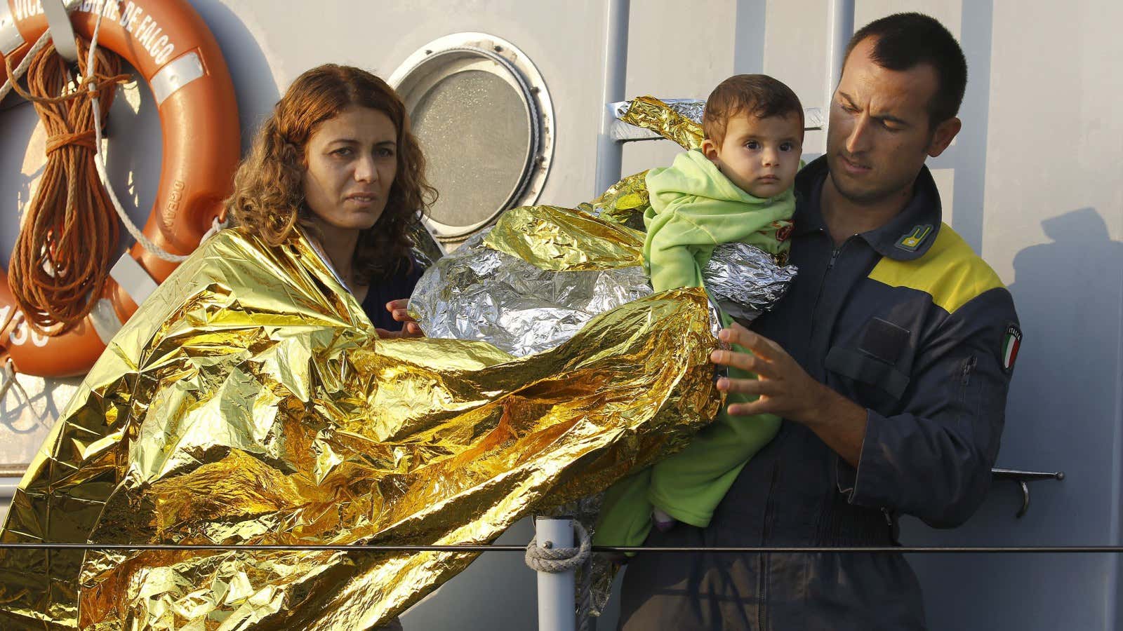 An Italian coast guard officer helps Syrian refugees from Kobani.