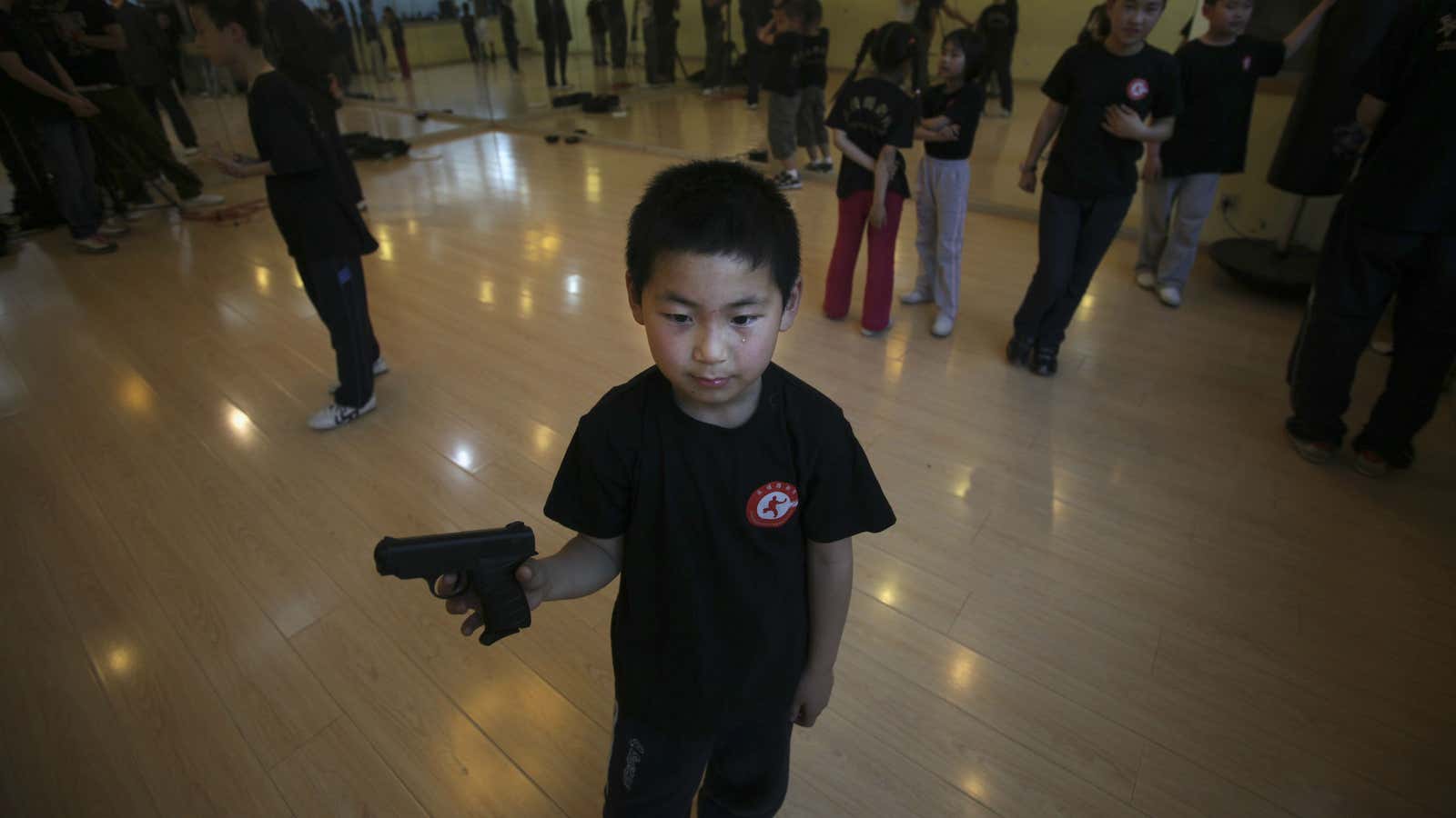 A primary student in China holds a toy gun during a self defense class. One way China dealt with a rampage of knife attacks at schools between 2010 and 2011 was giving children martial arts training.