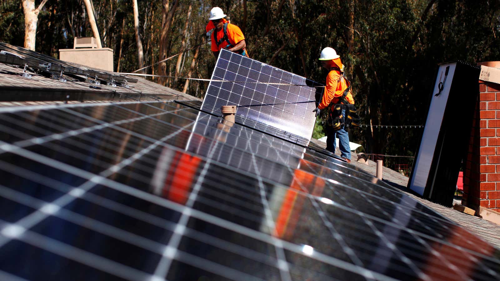 Solar panel installers work on a roof in California.