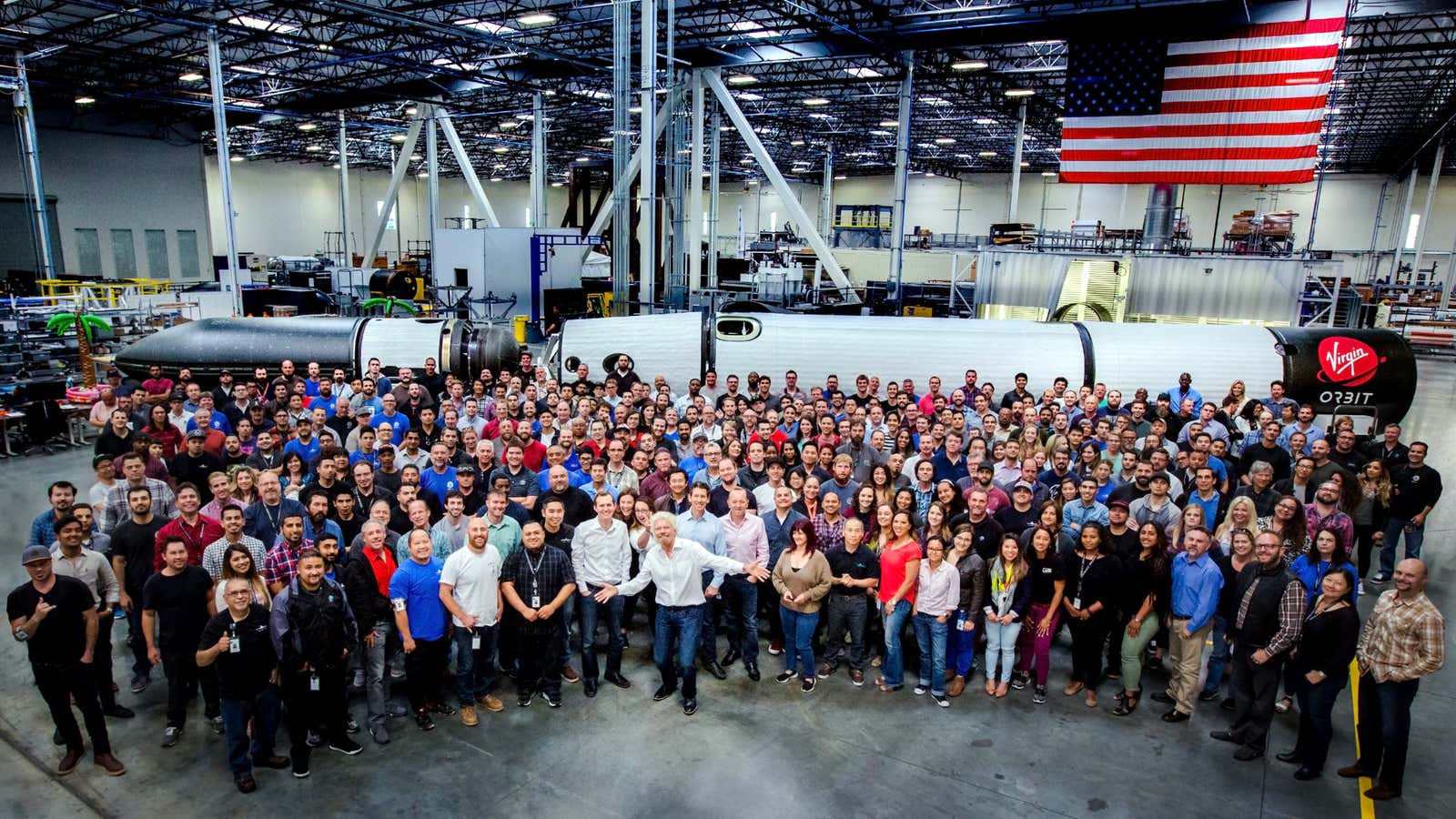 Richard Branson and company in front of a partially assembled Virgin Orbit rocket.