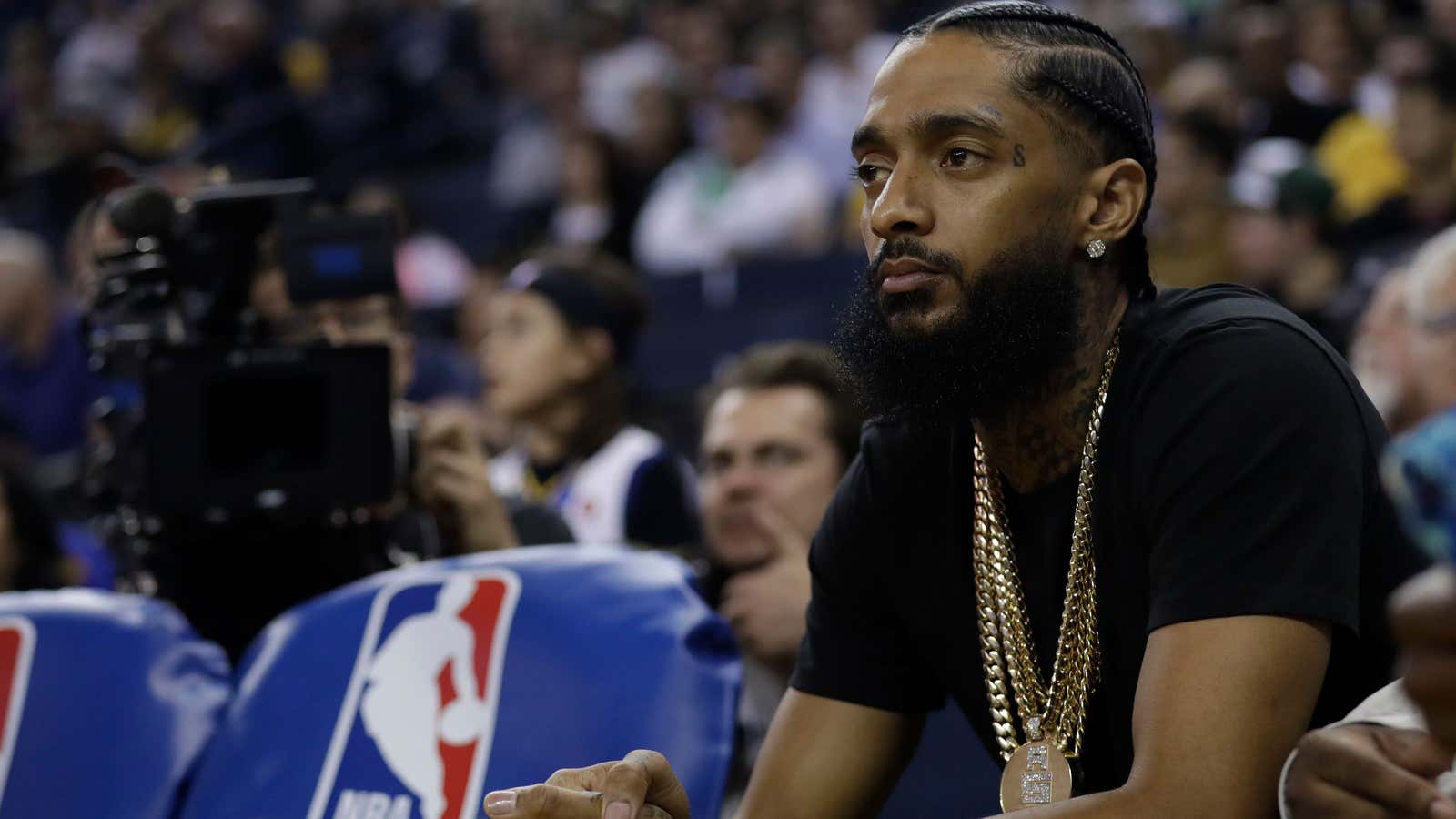 Rapper Nipsey Hussle watches an NBA basketball game, Mar. 29, 2018, in Oakland, Calif.