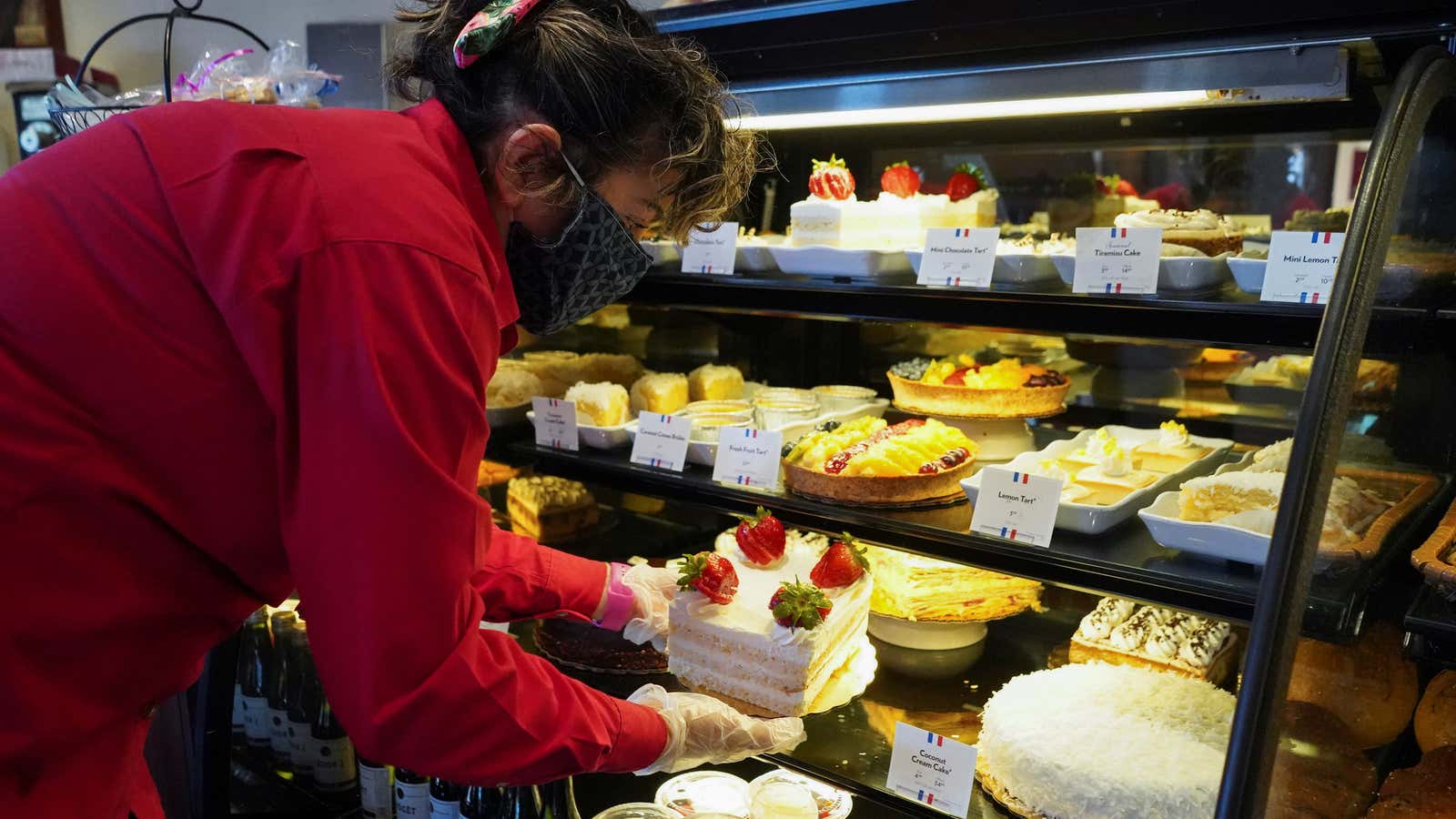 Flory Ramirez, a general manager of La Madeleine restaurant, wears a mask while handling cakes in the showcase as restaurants are reopened following the lifting of some restrictions in place to prevent the spread of coronavirus disease (COVID-19) in Houston, Texas, U.S., May 1, 2020.  REUTERS/Go Nakamura