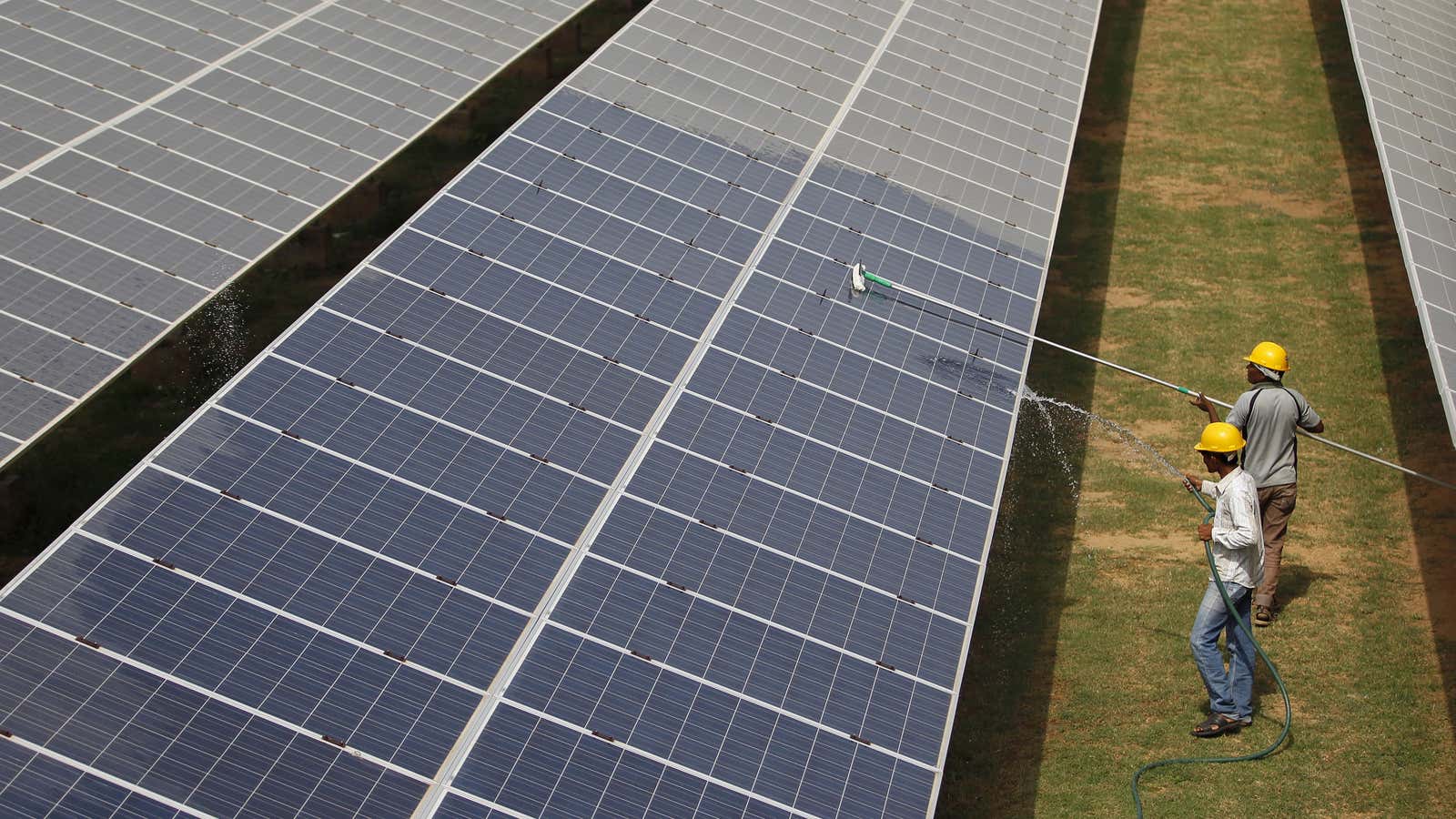 Workers clean photovoltaic panels inside a solar power plant in Gujarat, India.