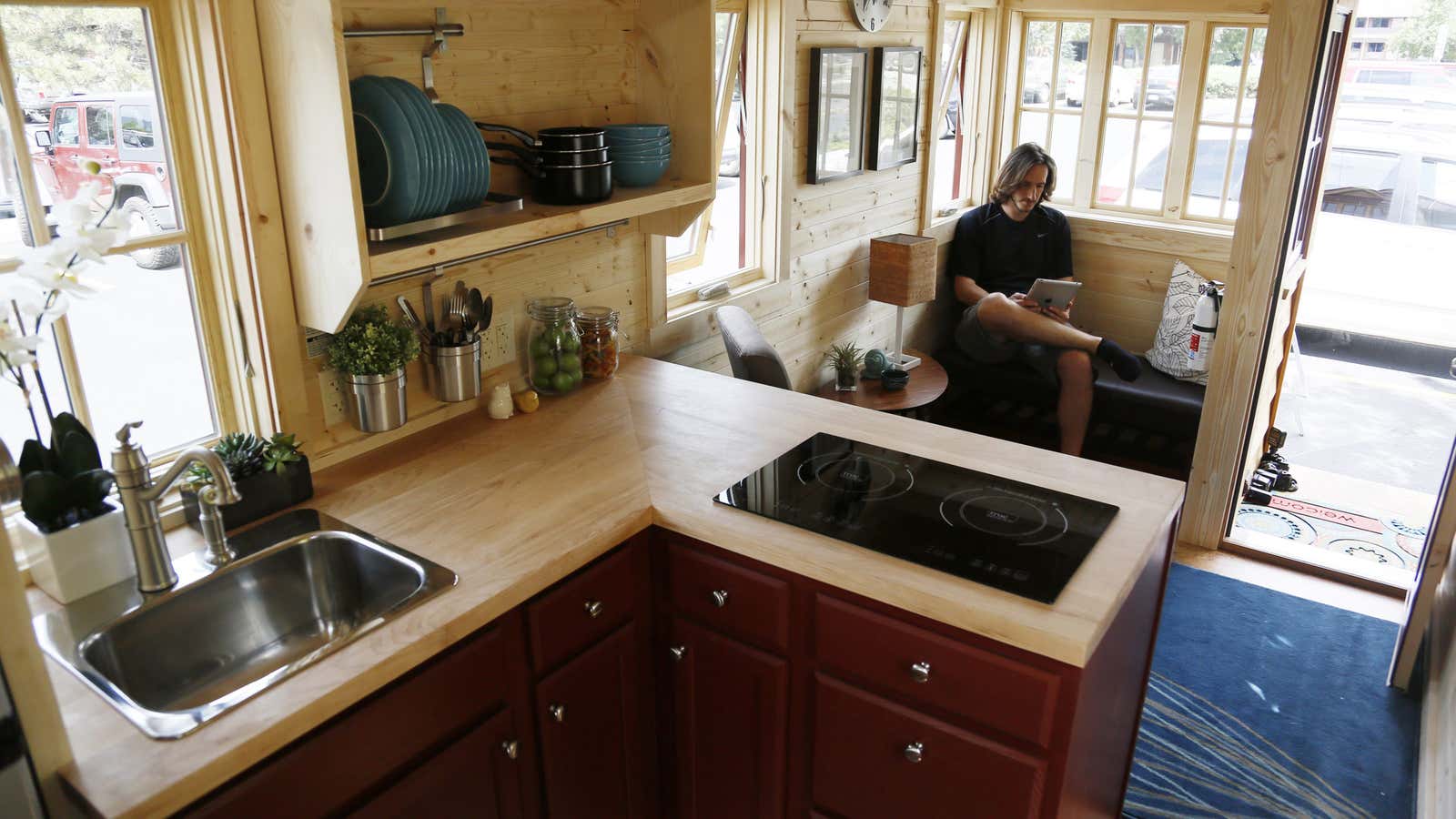 Guillaume Dutilh, a Tumbleweed workshop host poses in the living area of a Tumbleweed brand Cypress 24 model Tiny House on display in Boulder, Colorado August 4, 2014. The Tiny House Movement started some years ago with people around the world building really small living spaces and loving their new simplified lives. These tiny houses can range from 1,000 square feet (93 square meters) down to less than 100 square feet (9.3 square meters), and are certainly not ramshackle shacks. REUTERS/Rick Wilking (UNITED STATES – Tags: SOCIETY) – GM1EA850KL201