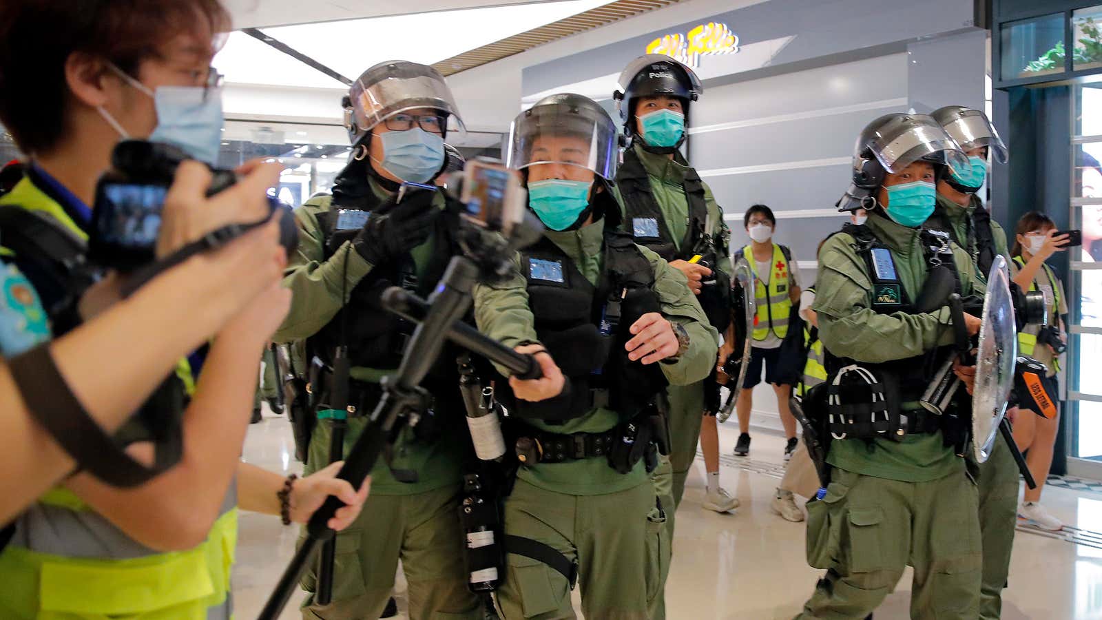 A police officer swats a reporter’s microphone in Hong Kong.