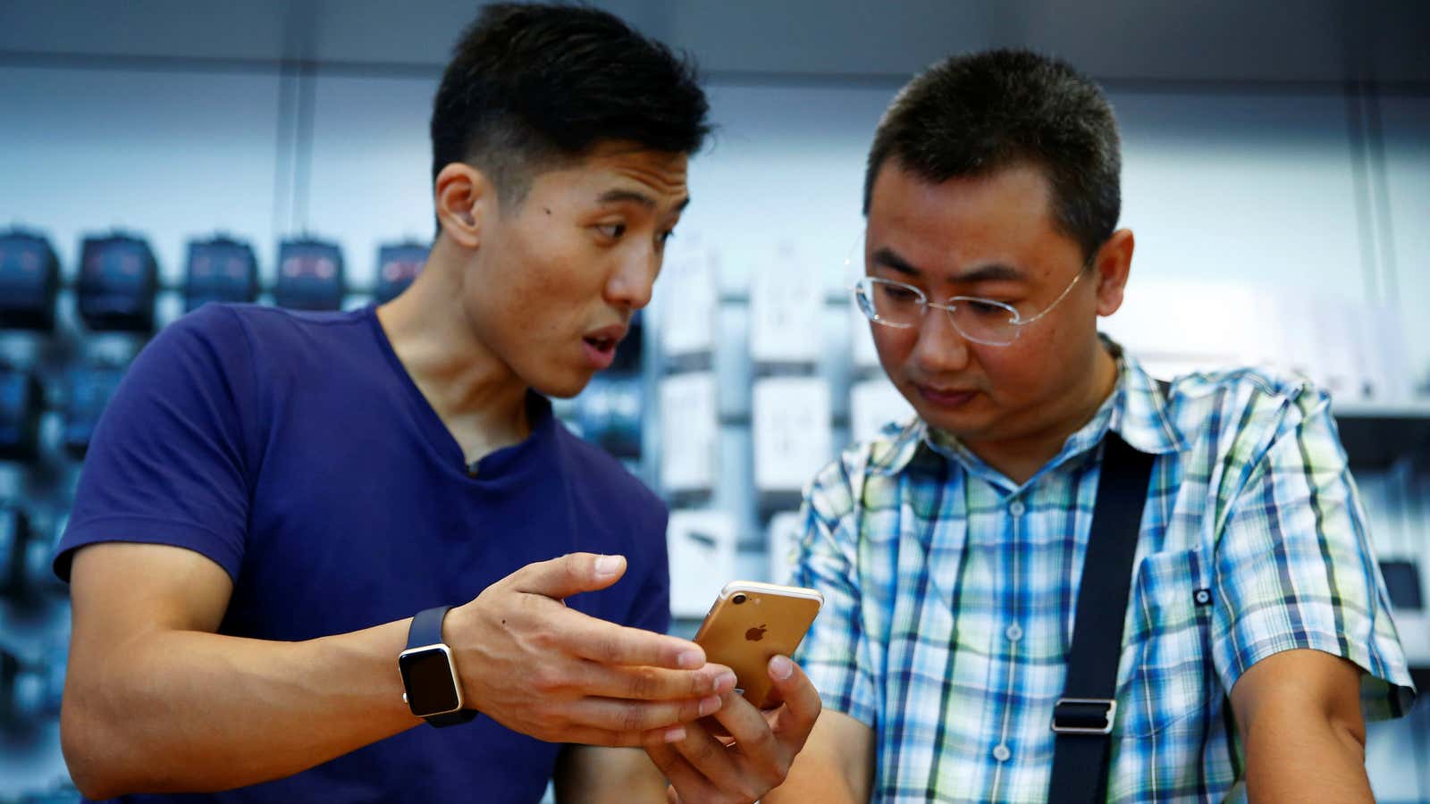 A staff member (L) explains Apple’s new iPhone 7 to a customer at an Apple store in Beijing, China