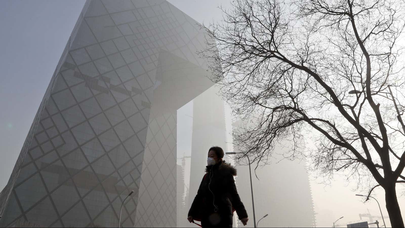 A Chinese woman wearing a protection mask walks near the iconic headquarters of China’s state broadcaster Central China Television (CCTV) at the Central Business District…