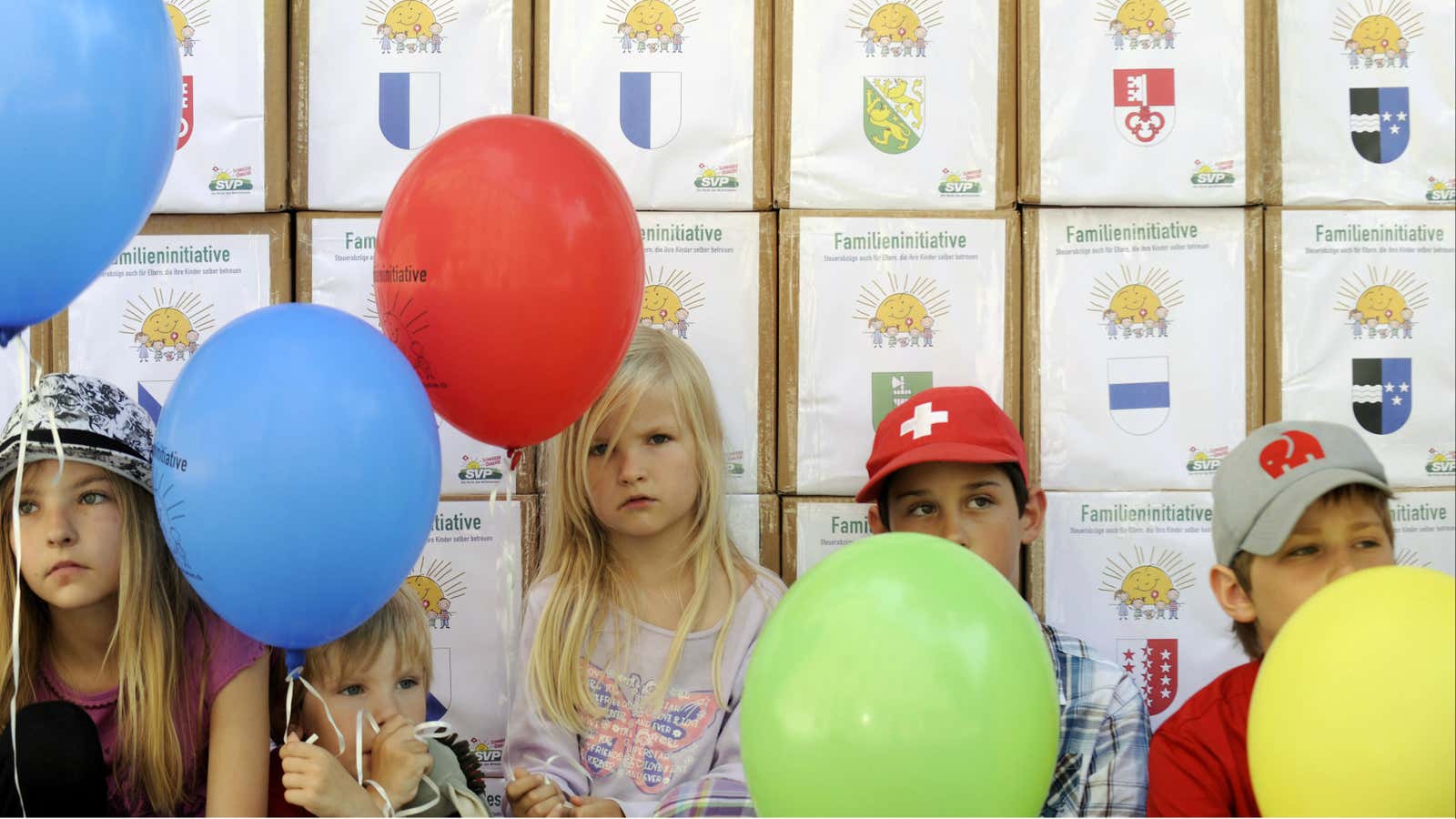 Children sit in front of boxes containing signatures for the Swiss People’s Party (SVP) “Familiy Initiative” before a handover ceremony in Bern July 12, 2011.…