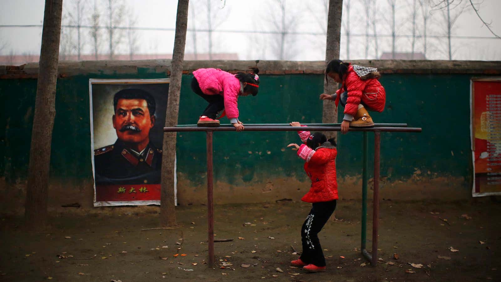 Students play next to a portrait of Soviet leader Joseph Stalin.