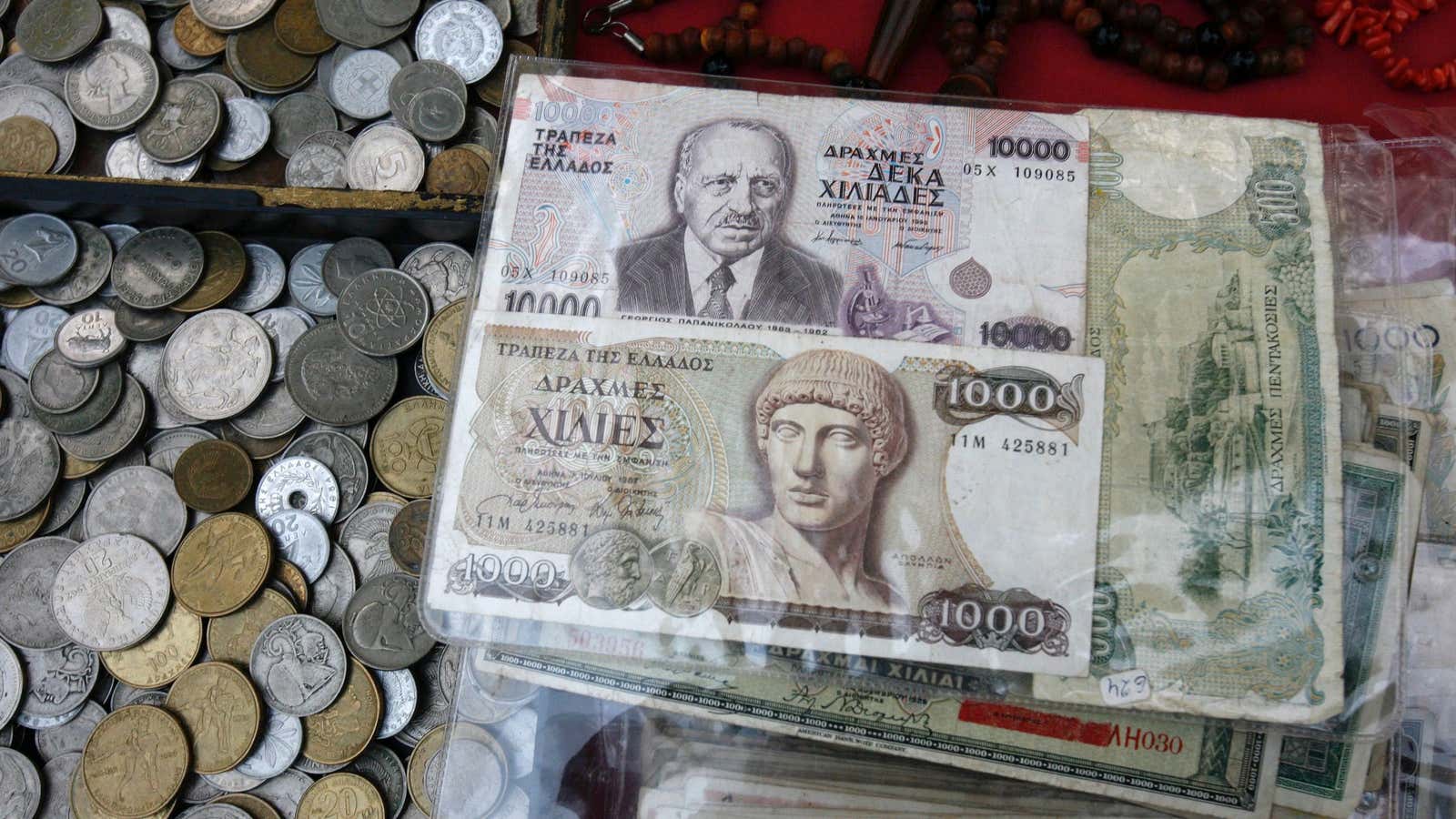 Old Greek drachma coins and notes sit arranged for sale during an antique bazaar at the northern port city of Thessaloniki, Greece, in 2012.