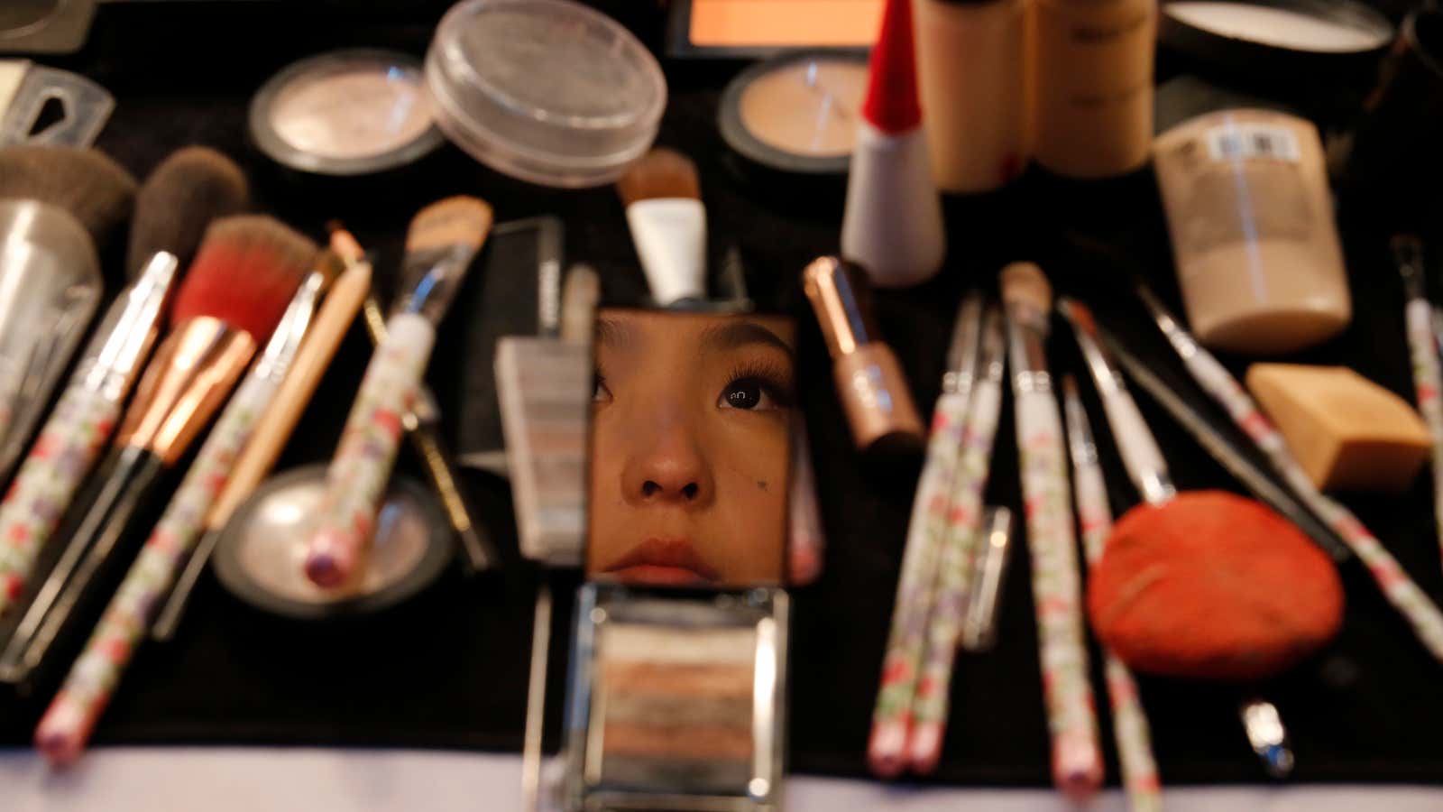 A contestant is reflected off a mirror backstage as she puts on make-up prior to the China Super Model Final during China Fashion Week in…