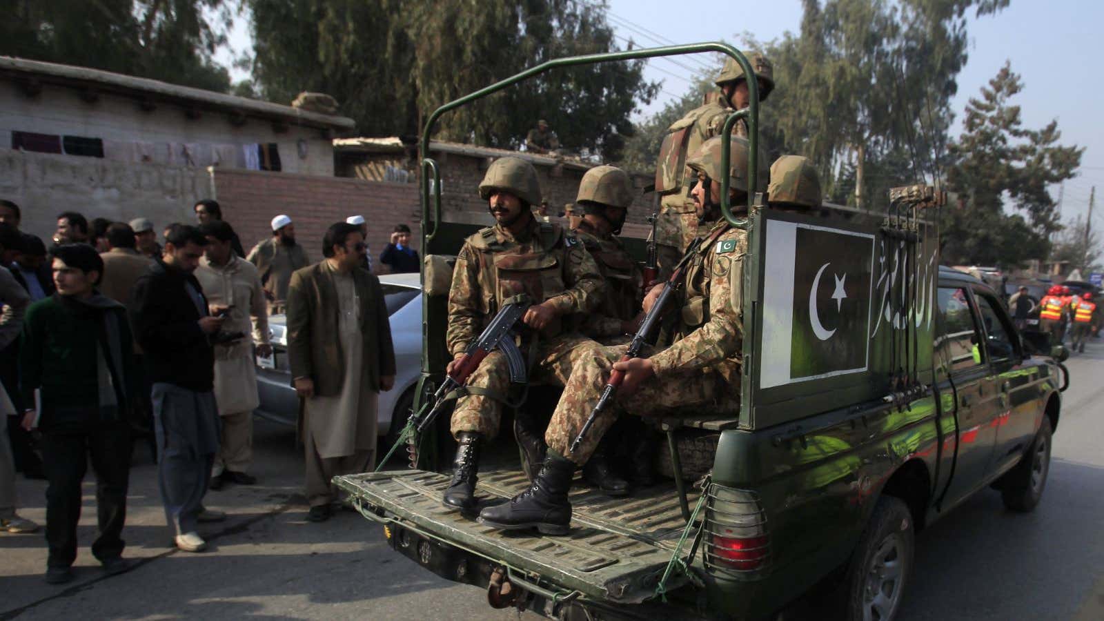 Pakistani security forces drive on a road leading to the Army Public School in Peshawar.