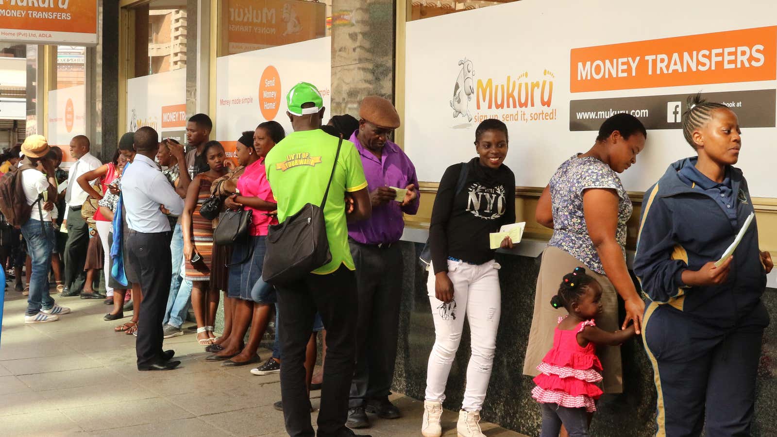 People queue to withdraw US dollars from a money transfer shop in Harare.