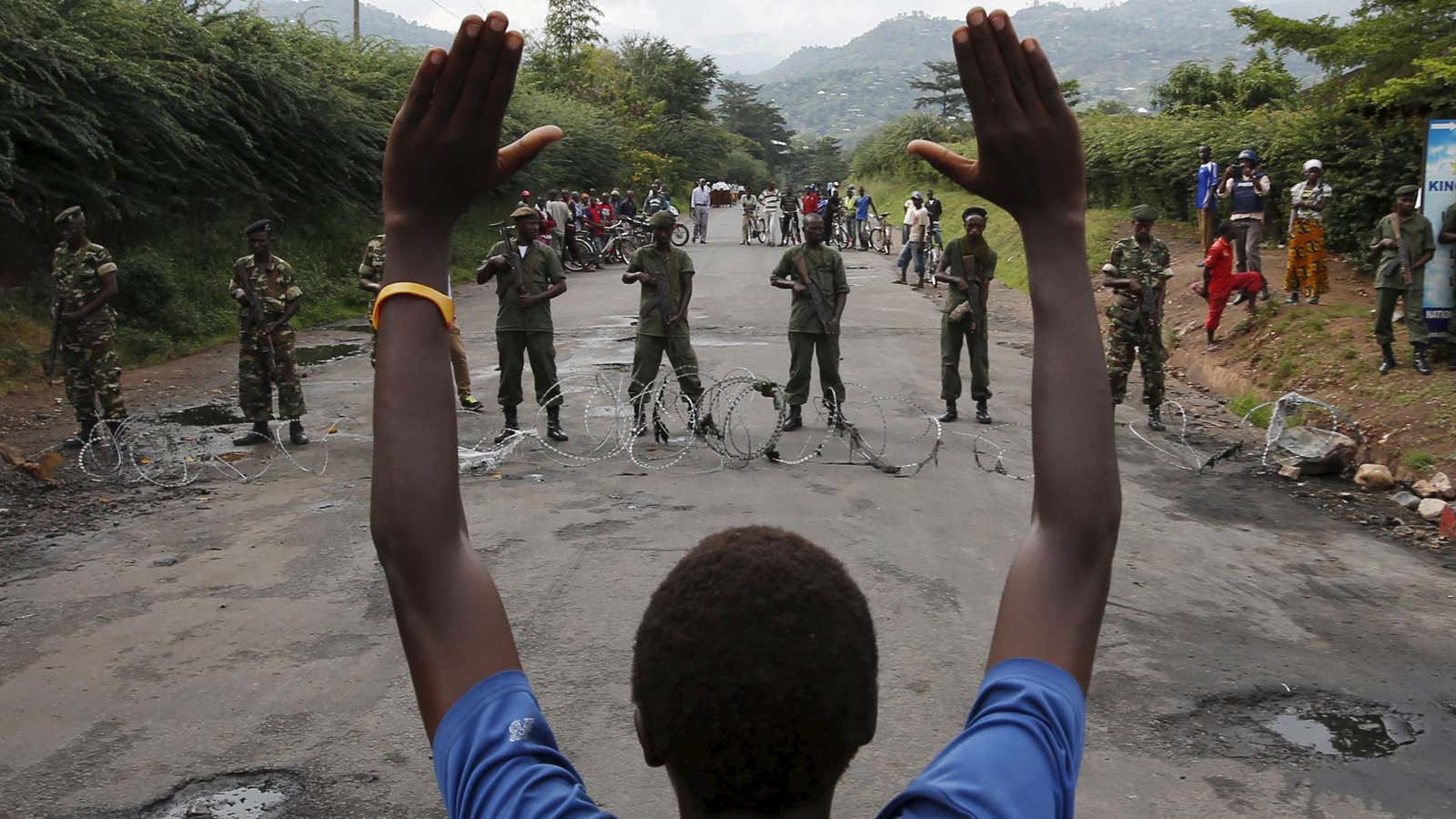 A protester holds his hands up in front of soldiers in Burundi.